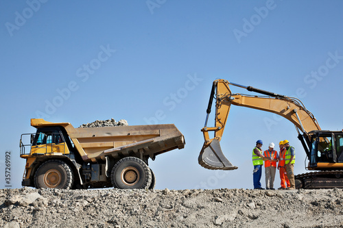 Canvas Print Workers talking by machinery in quarry