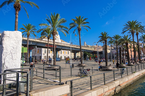 Genoa, Italy - August 18, 2019: The Promenade of Porto Antico di Genova with tourists and locals and the Palazzo San Giorgio in the background photo