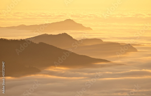 Aerial view of mountaintops over clouds at sunset © Deb Casso/KOTO