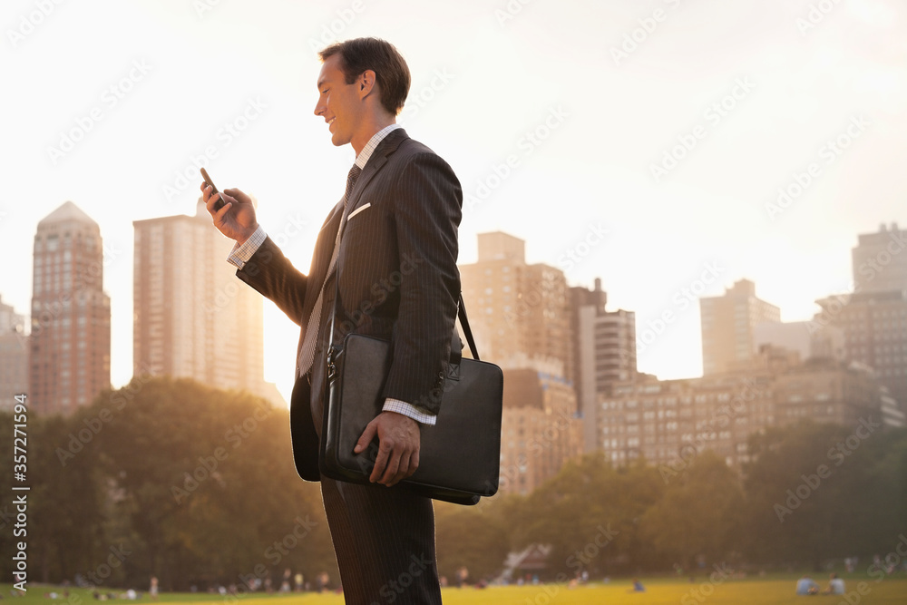 Businessman using cell phone in urban park
