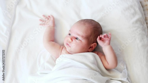 little baby newborn lying lies on white showing performing moro reflex