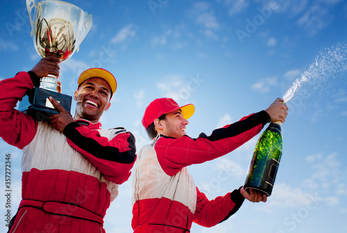 Fotografiet Racers holding trophy and champagne