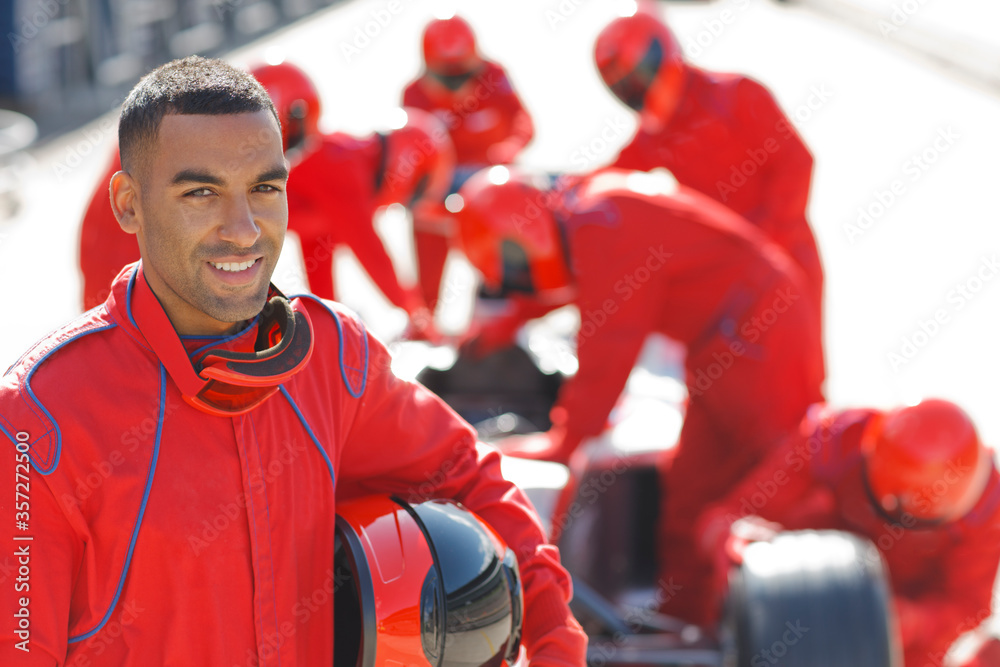 Fototapeta premium Racer standing with team in pit stop
