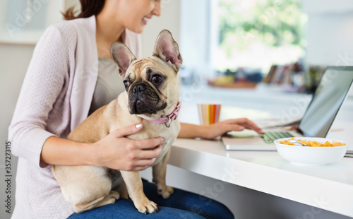 Woman using laptop with dog on lap