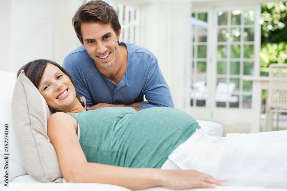 Man sitting next to pregnant woman resting on bed Man sitting next to pregnant woman resting on bed