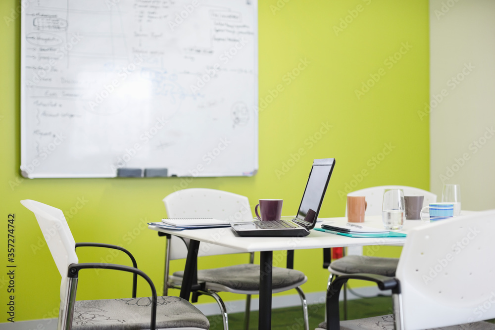 Fototapeta premium Laptop and coffee cups on meeting table