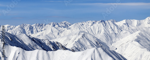 Panoramic view on high snowy mountains and blue sky with clouds