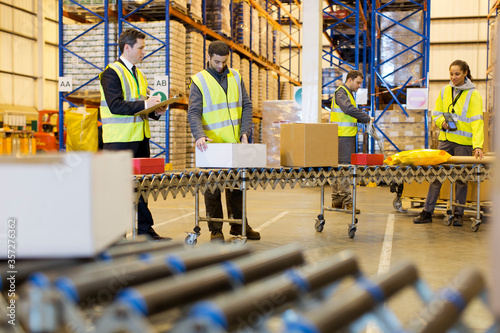 Workers checking packages on conveyor belt in warehouse