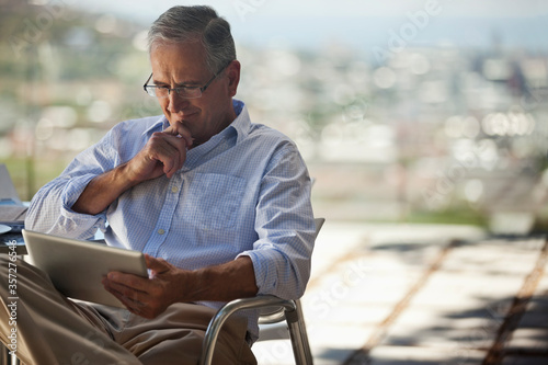 Older man using tablet computer outdoors photo