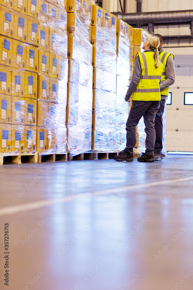 Workers examining stacks of boxes in warehouse Workers examining stacks of boxes in warehouse