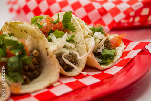 Obraz na płótnie Tacos y tortas de barbacoa sobre mantel de cuadros rojos y fondo blanco w salonie