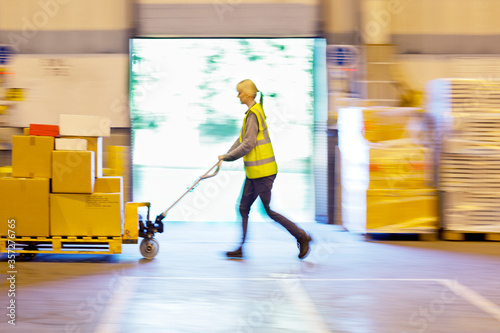Blurred view of worker carting boxes in warehouse