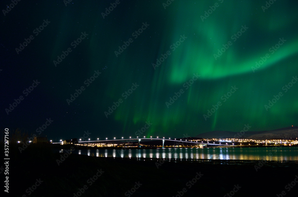 aurora borealis over tromso city island, fjord and snowy mountain