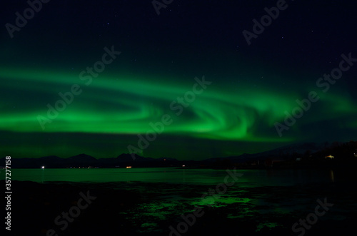 strong aurora borealis on autumn sky with reflection in cold autumn fjord © Arcticphotoworks