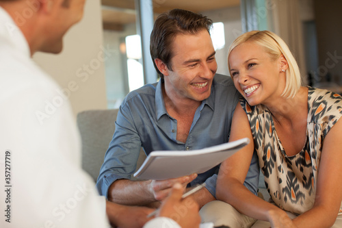 Financial advisor talking to couple on sofa photo