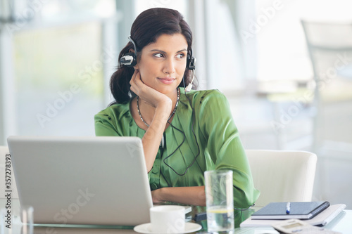 Φωτογραφία Businesswoman wearing headphones at desk