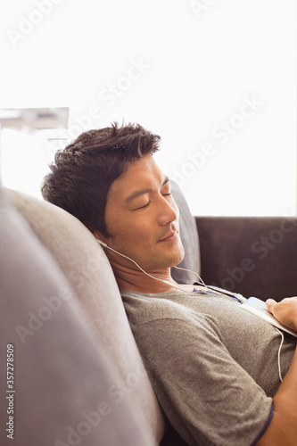 Man listening to headphones on sofa photo