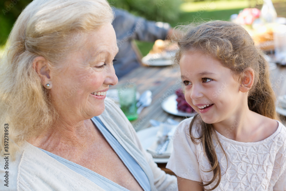 Older woman sitting with granddaughter outdoors Older woman sitting with granddaughter outdoors