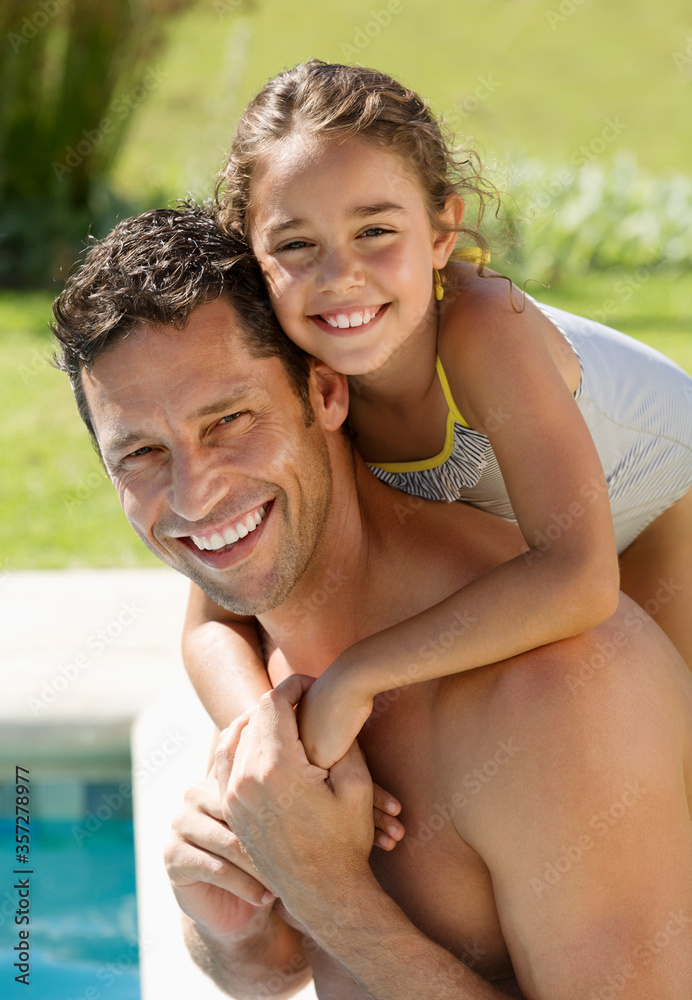 Father and daughter smiling by swimming pool Father and daughter smiling by swimming pool