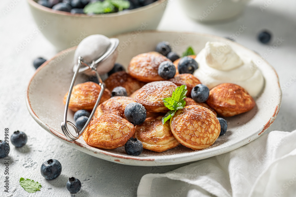 Homemade poffertjes with blueberries and powdered sugar Homemade poffertjes with blueberries and powdered sugar