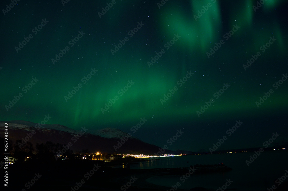 aurora borealis over fjord and sandy beach