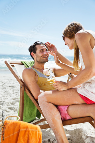 Woman applying sunscreen to man's nose at beach © Dan Dalton/KOTO