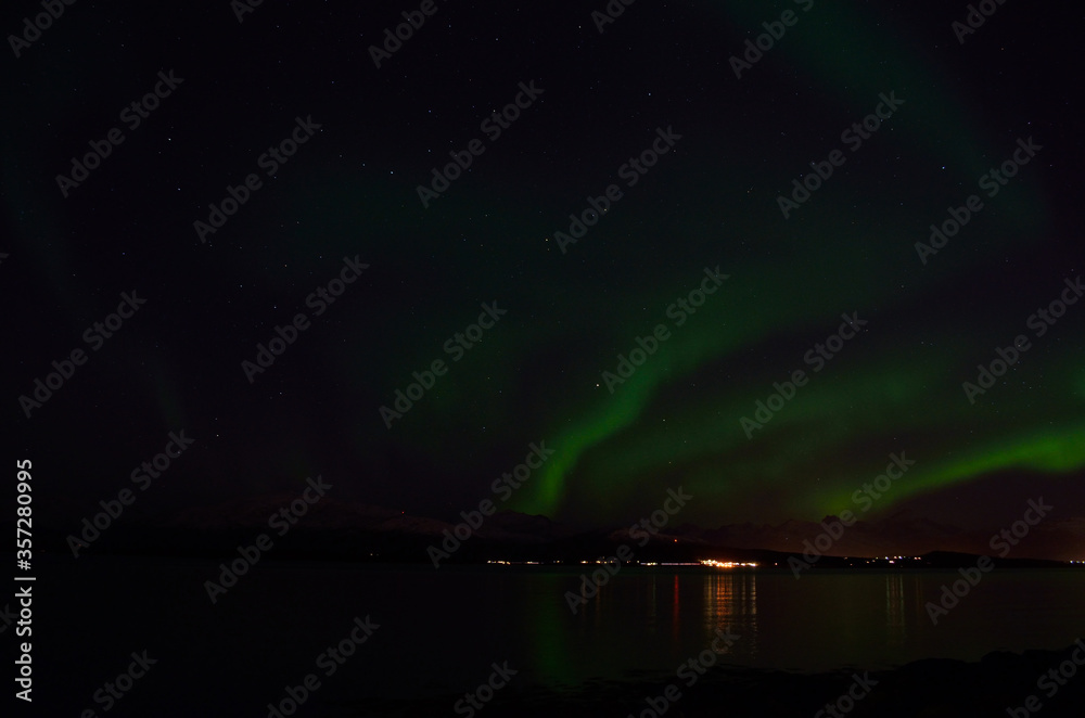 aurora borealis over cold fjord and mountain in autumn