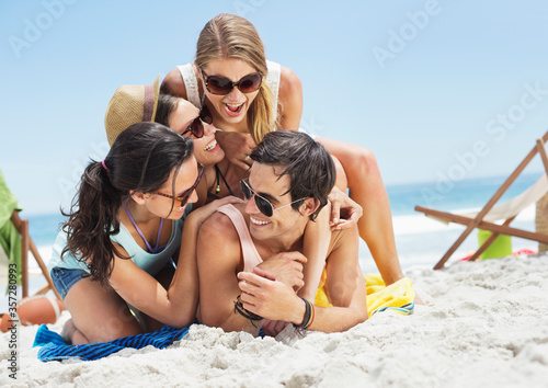 Happy friends laying on top of each other on beach