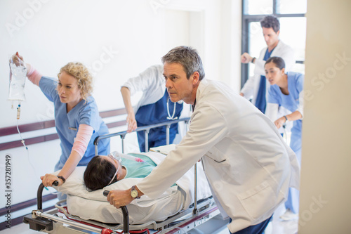 Canvas Print Doctors and nurses rushing patient on stretcher down hospital corridor