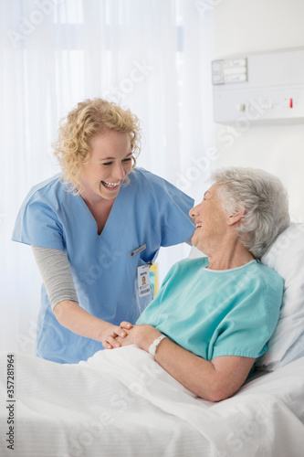Nurse and senior patient talking in hospital room