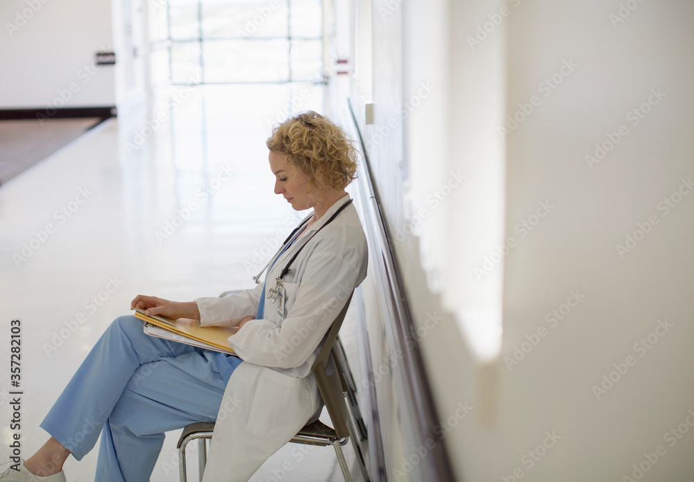 Doctor reviewing medical chart in hospital corridor Doctor reviewing medical chart in hospital corridor
