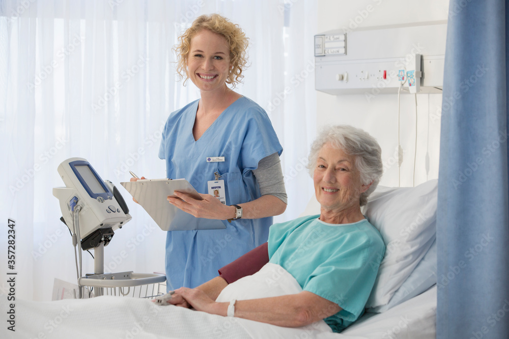 Obraz premium Portrait of smiling nurse and senior patient in hospital room