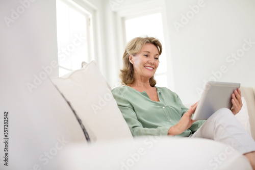 Free Download Senior woman using digital tablet on sofa - GFXLoad