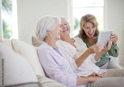 Older women using digital tablet on sofa