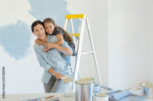 Portrait of mother and daughter hugging near paint supplies