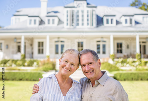 Portrait of smiling senior couple in front of house