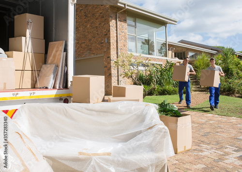 Movers carrying cardboard boxes from house to moving van photo