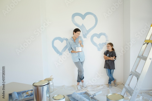 Mother and daughter painting blue hearts on wall