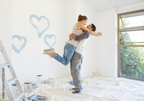 Foto Couple painting blue hearts on wall