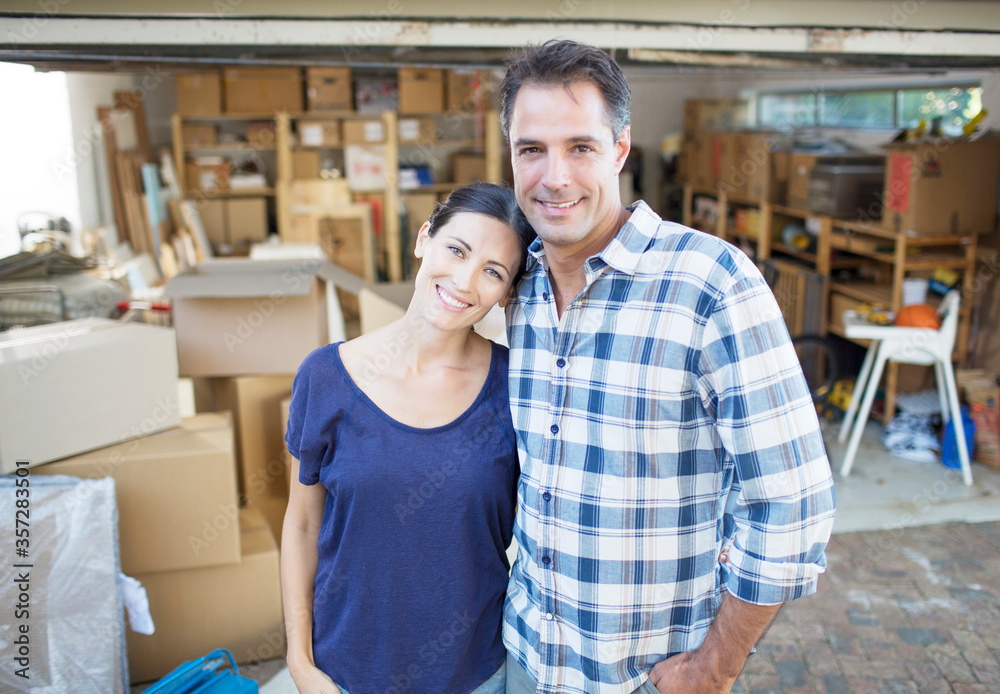 Obraz premium Portrait of smiling couple outside garage among cardboard boxes