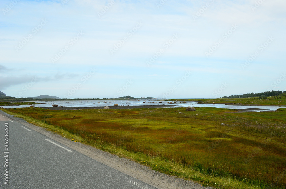 long strait road with ocean water on sides and mighty mountains in summer, vesteraalen