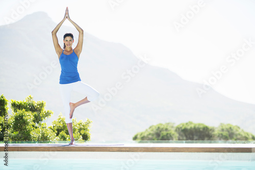 Woman practicing yoga at poolside