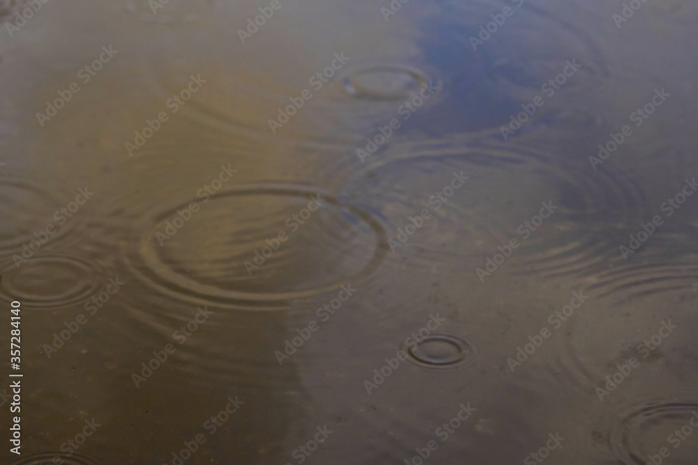 Drops of rain bubbling in a puddle with the reflection of light Drops of rain bubbling in a puddle with the reflection of light