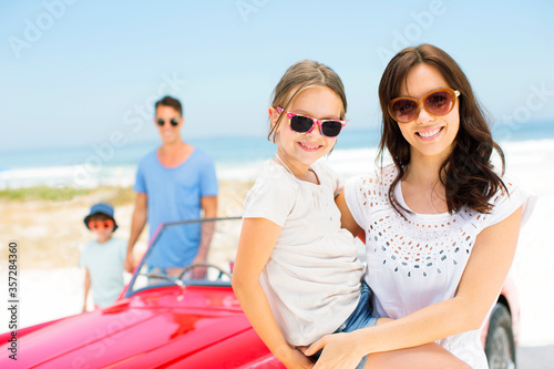 Mother and daughter smiling by convertible on beach © Dan Dalton/KOTO