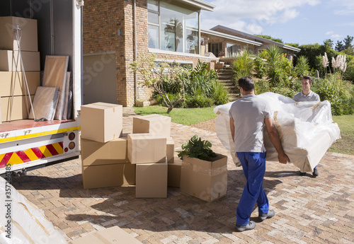 Movers carrying sofa from moving van to house photo
