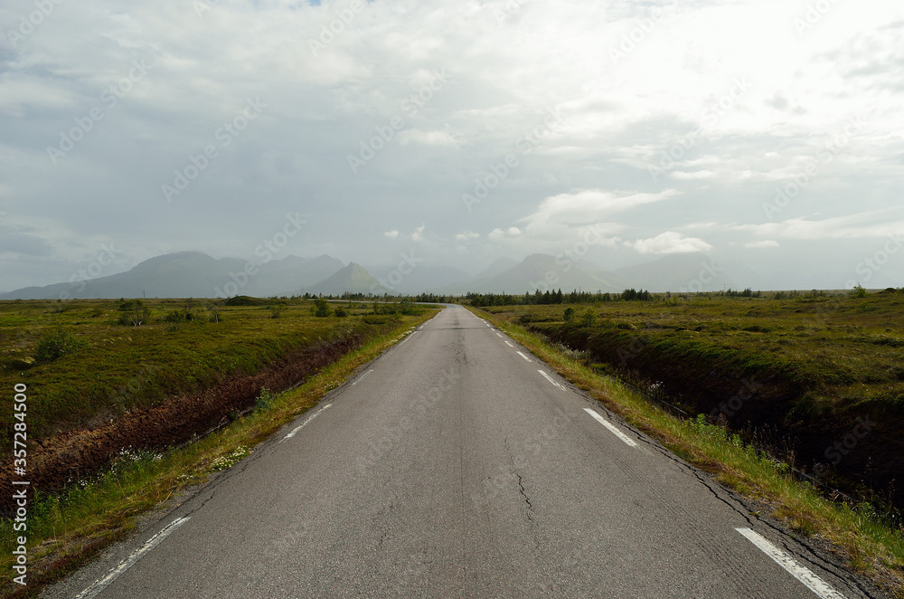 long road throug flat landscape with mountain and fog in backdrop long road throug flat landscape with mountain and fog in backdrop