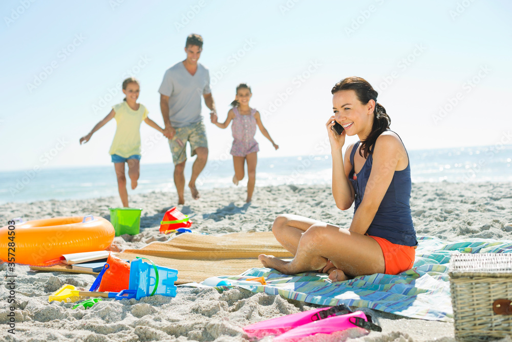 Fototapeta premium Woman talking on cell phone at beach