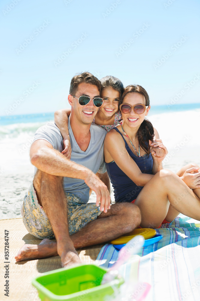 Obraz premium Portrait of smiling family hugging on beach