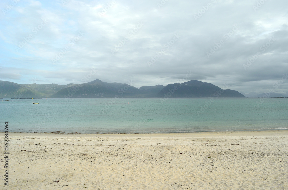 white beach sand, blue sea and mighty mountains in summer