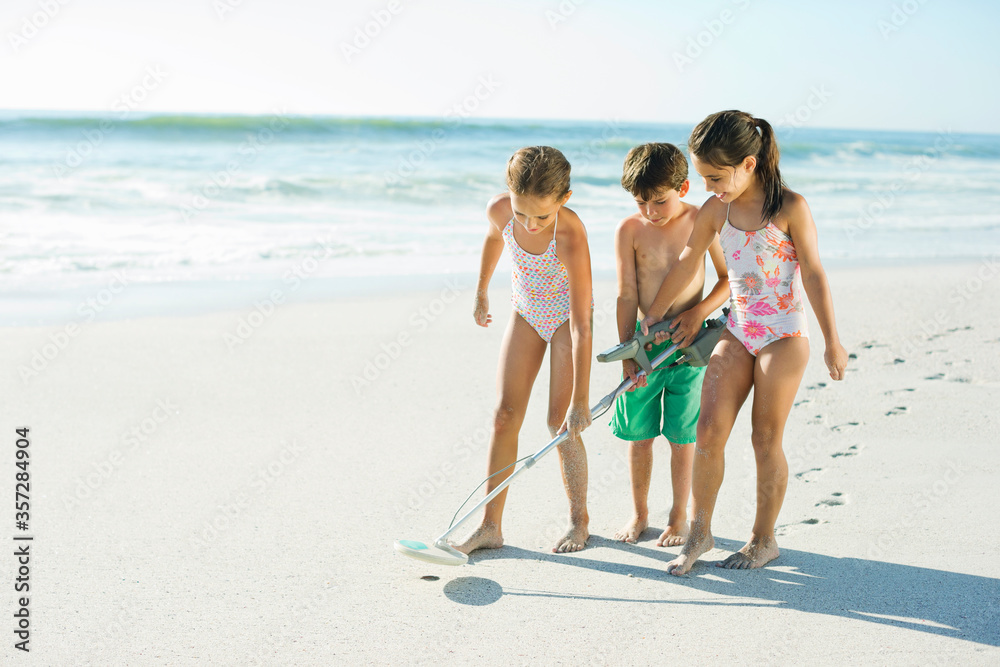 Children using metal detector on beach - obrazy, fototapety, plakaty 